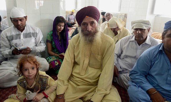 In this photograph taken on April 14, 2015, Harbhan Singh (C), who migrated from restive Tirah Valley in Khyber tribal agency go to flee a military operation, sits at the Gurdwara Panja Sahib in Hasanabdal, during the annual Baisakhi festival. — AFP